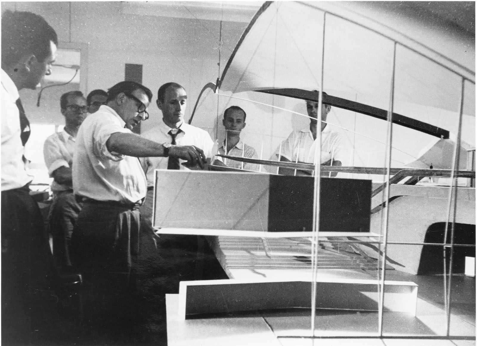 Photo of Eero Saarinen showing his model of the TWA Terminal to other architects.