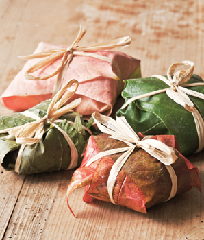 Red- and green-leaf wrapped packages of cheese, each tied prettily with a raffia ribbon tied with a bow at the top like a present