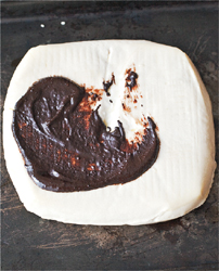 A smear of cocoa paste atop a rectangular block of white cheese