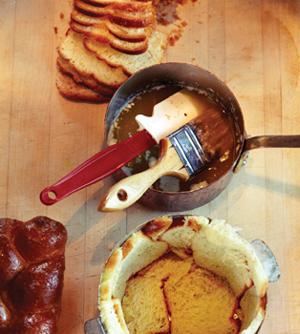 A pastry brush and spatula in a pot of sauce