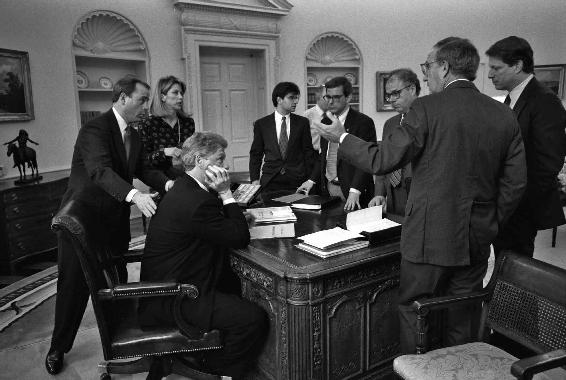 Chief of Staff Thomas F. “Mack” McLarty (hand on Clinton’s back), Bill Clinton, and a gaggle of White House officials. Early in his presidency, meetings were disorganized, standing-room-only affairs: “Every Tom, Dick, and Harry” was there, complained Leon Panetta.  Photo by Robert McNeely, Courtesy William J. Clinton Presidential Library