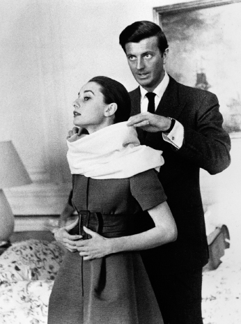 Givenchy adjusts a scarf on Audrey during a fitting (1958). She was his muse.