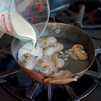 Adding cream to whole oysters in a copper skillet