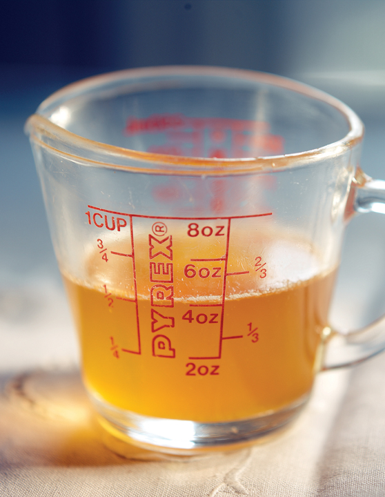 A 1-cup Pyrex measuring cup filled halfway with golden stock