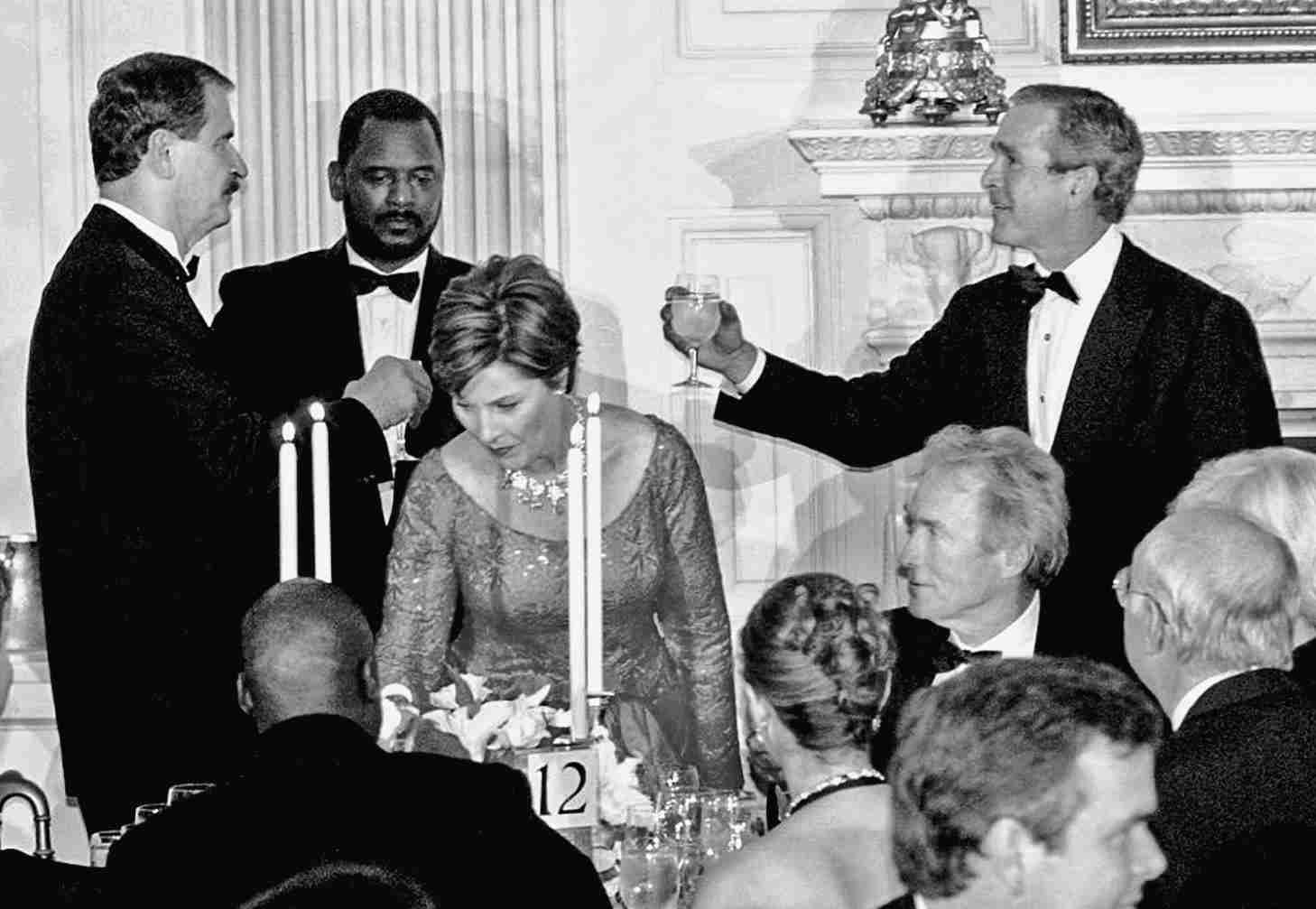 President George W. Bush (R) and Mexican President Vicente Fox (L) toasting each other as actor Clint Eastwood, Mrs. Bush, Senator Phil Gramm and Governor Jeb Bush sit in the foreground during the state dinner at the White House.    (Photo by Mai/Getty Images)