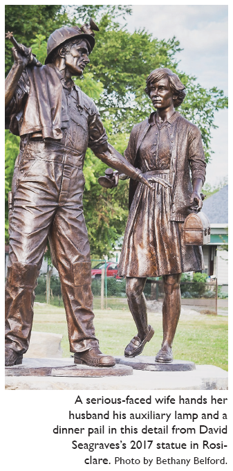 Image: A serious-faced wife hands her husband his auxiliary lamp and a dinner pail in this detail from David Seagraves’s 2017 statue in Rosiclare. Photo by Bethany Belford.