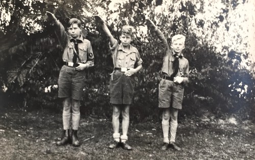 Die Jungen Heinz, Peter und Helmuth Göring stehen eingereiht und in Uniform im Garten. Sie heben den Arm zum Hitlergruß.