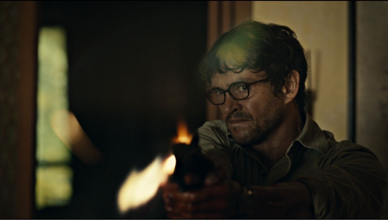 Frame from Hannibal pilot showing close up of Will Graham firing his handgun to stop a serial killer.