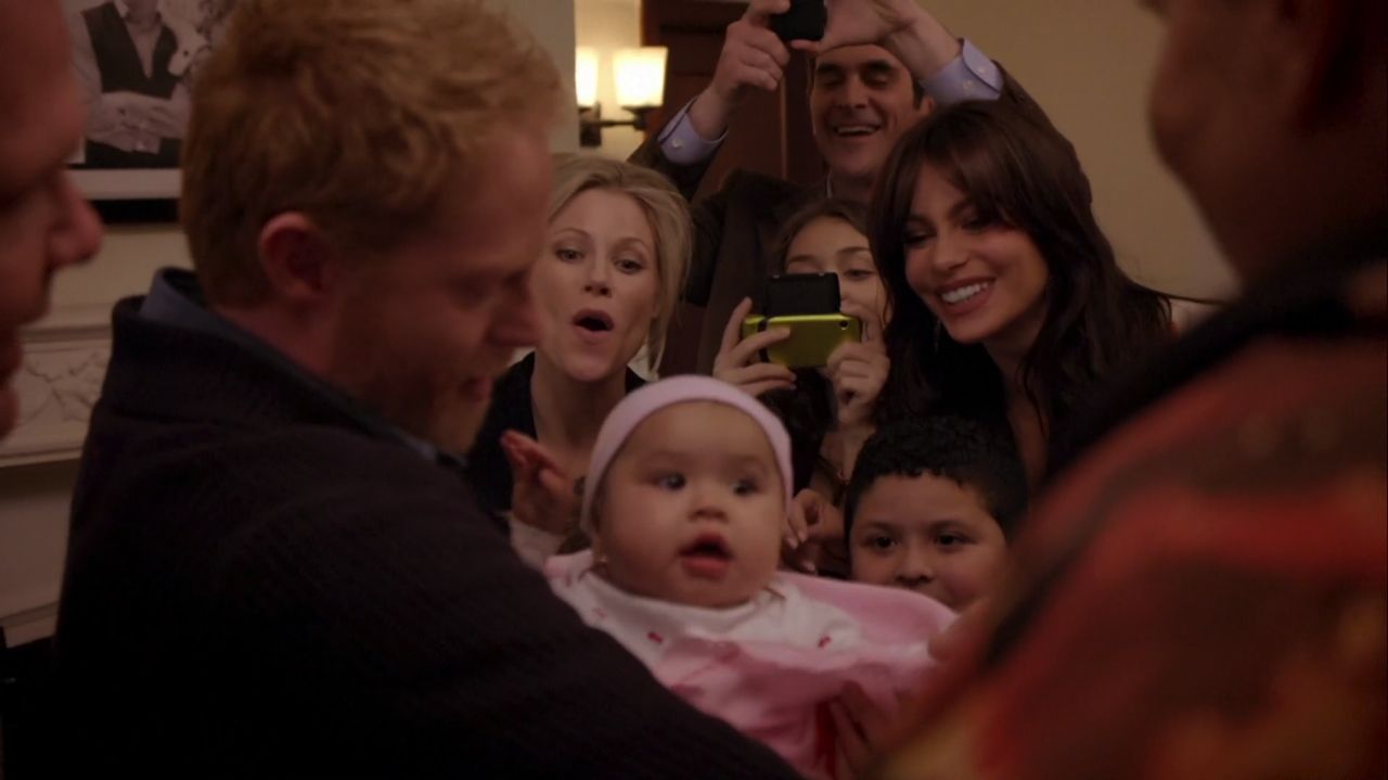 In frame from Modern Family pilot, Mitchell Pritchett holds his new daughter, Lily, surrounded by his family.