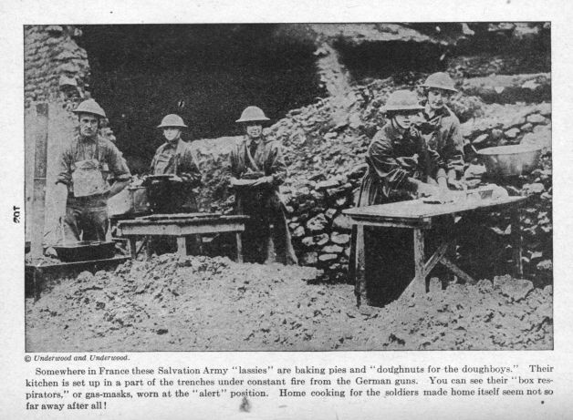 Somewhere in France these Salvation Army "lassies" are baking pies and "doughnuts for the doughboys." Their kitchen is set up in a part of the trenches under constant fire from the German guns. You can see their "box respirators," or gas-masks, worn at the "alert" position. Home cooking for the soldiers made home itself seem not so far away after all!