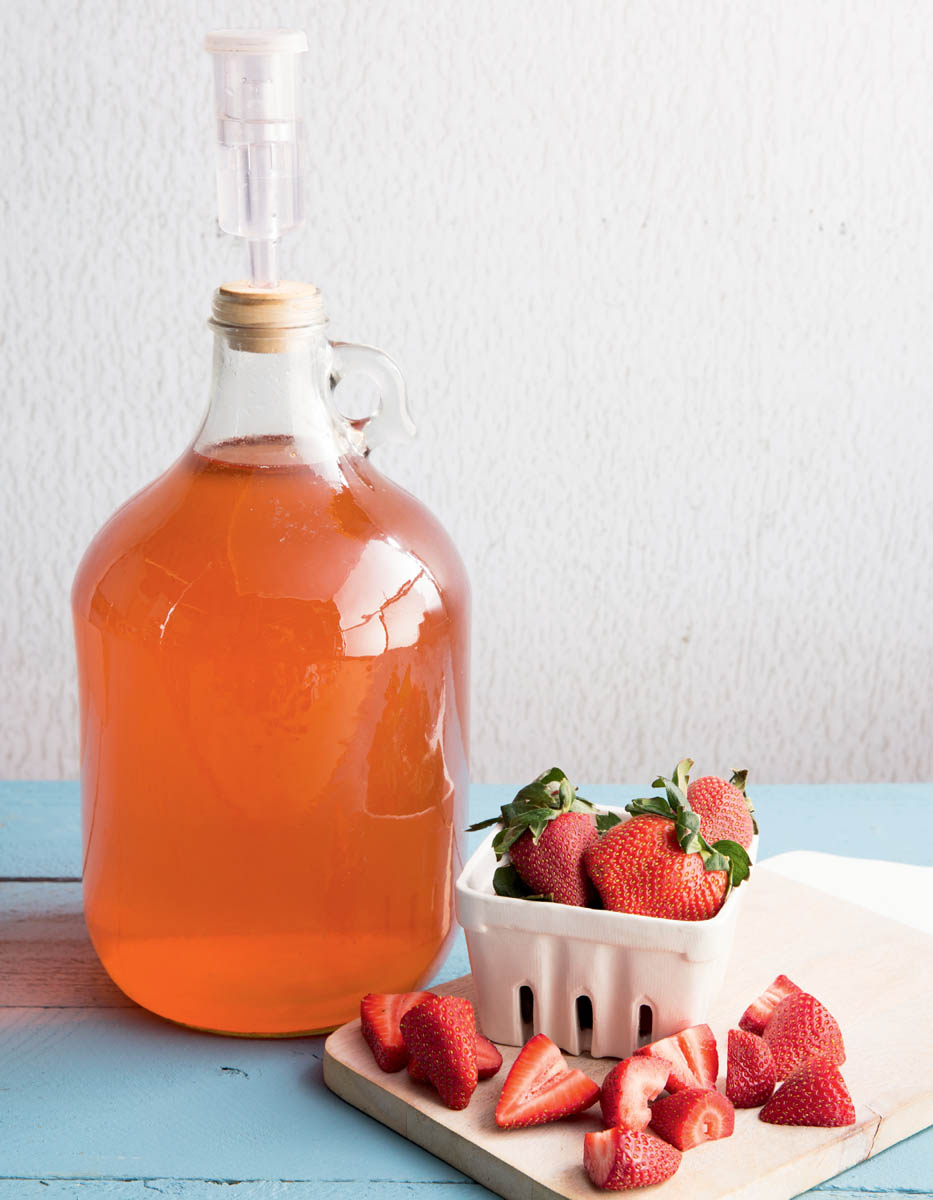 chapter opener photo of wine fermenting in carboy and a cutting board with fresh whole and sliced strawberries