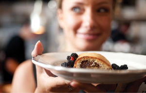 A grinning waitres holding up a plate of breakfast