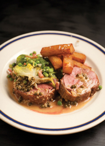 Duck Steak au Poivre, sliced, and served on a white ceramic plate with a serving of peas and a side of fries