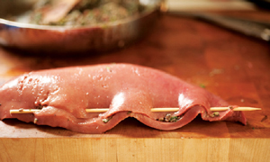 A stuffed calf liver with a skewer holding the end closed