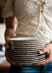 A girl carrying a stack of round plates