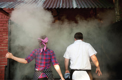 A young man and woman standing on front of a smoke-filled entrance