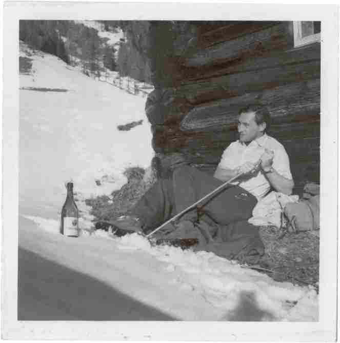 A photograph of a young Nigel Buxton, sitting outside a sunny chalet, chilling a bottle of wine in the snow