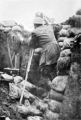 FILMING THE PRELIMINARY BOMBARDMENT OF THE BIG PUSH, JULY 1ST, 1916. A FEW MINUTES AFTER THIS PHOTOGRAPH WAS TAKEN A SHELL BURST WITHIN SIX YARDS, SMASHING DOWN THE TRENCH WALLS AND HALF BURYING ME. NOTE THE SANDBAG ON A WIRE IN FRONT OF MY CAMERA FOR "CAMOUFLAGE"