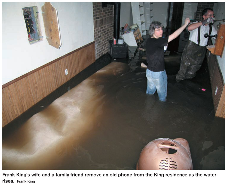 Frank King’s wife and a family friend remove an old phone from the King residence as the water rises. Frank King