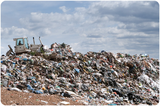 Bulldozer working on mountain of garbage in landfill