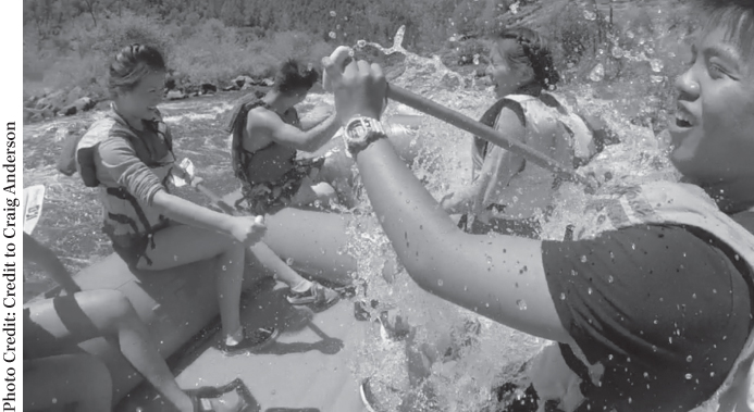 Photograph of teenagers navigating white-water rapids on a river in the Sierra Nevada Mountains.