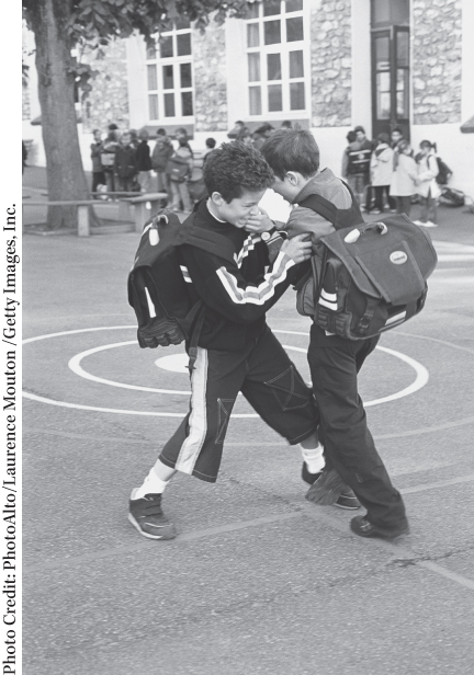 Photograph of two boys, with school bags on their back, involved in a fight in their school ground.