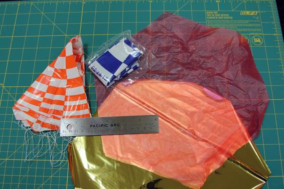 Parachutes are usually made from thin plastic. Shown here are two preassembled parachutes from the Estes Designer’s Special and two parachute canopies, one cut from a plastic bag and another cut from a Mylar balloon.