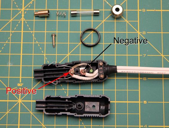 Fasten the wire connected to the black battery clip to the screw closest to the entry point for the wire, and the wire connected to the red battery clip to the farther screw, then reassemble the plug.