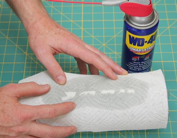 After removing the loose parts of the label by hand, soak the remaining scraps and glue on the outside of the bottle in WD-40 for a couple of hours. The scraps of label and glue will wipe away.