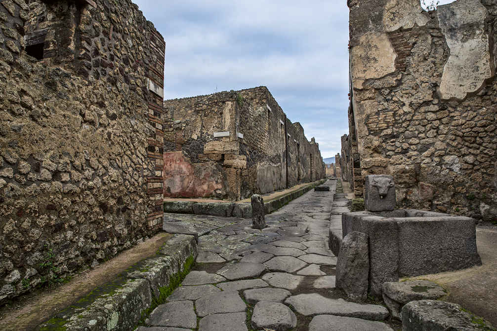 4b – Eine Straßenkreuzung Pompejis mit einem der öffentlichen Brunnen, die an das Aquädukt angeschlossen waren.