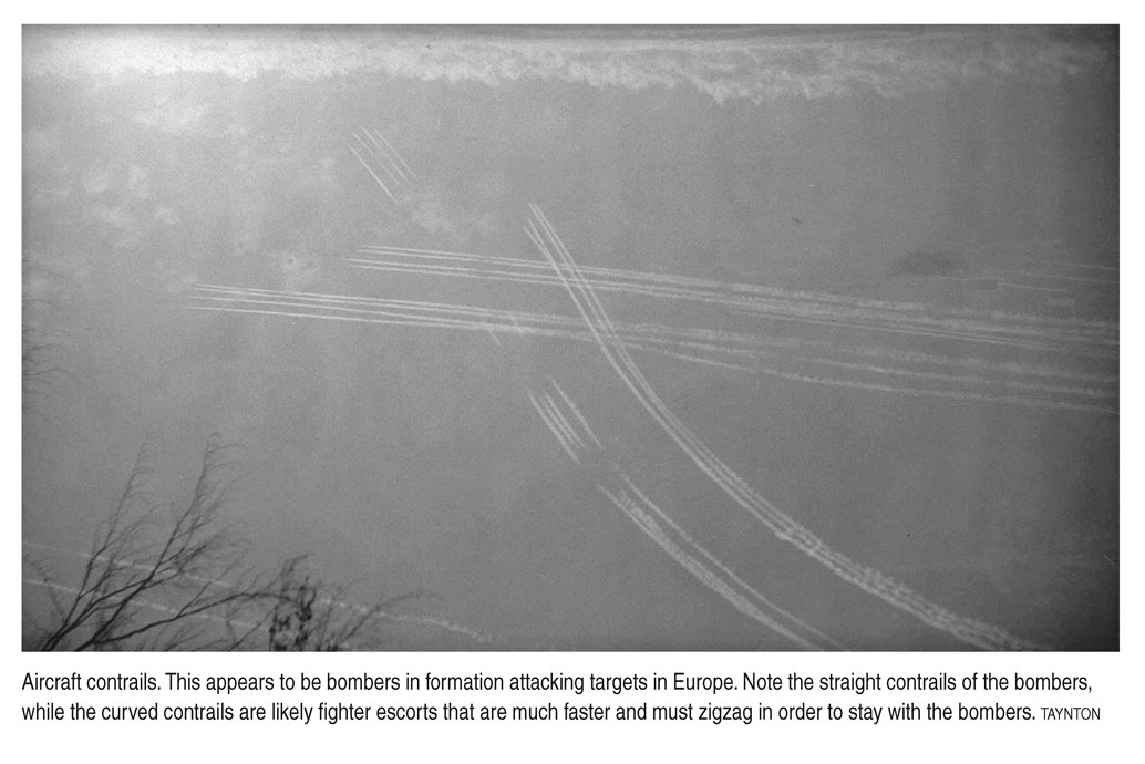 Aircraft contrails. This appears to be bombers in formation attacking targets in Europe. Note the straight contrails of the bombers, while the curved contrails are likely fighter escorts that are much faster and must zigzag in order to stay with the bombers. TAYNTON