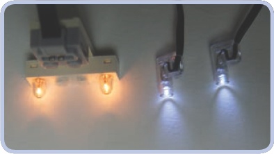 A 1×4-stud 9V brick with lights (left) and a pair of Power Functions LED lights (right). Note the difference in the color and direction of the light.