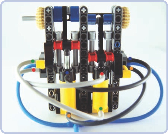 A two-cylinder engine with sliders. The colored dots show which ports are connected. The sliders are built around the red pieces, each moving along two light grey axles. They keep the cylinders’ motion in a straight line and then transfer the motion to the cams (blue). Note that the extension of the cylinders is limited to 3 studs rather than 4, but thanks to this limitation, the sliders can also be used to control the valves.