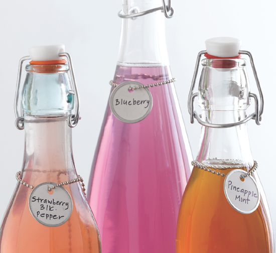 Glass bottles full over colorful syrups and labels with round handwritten tags