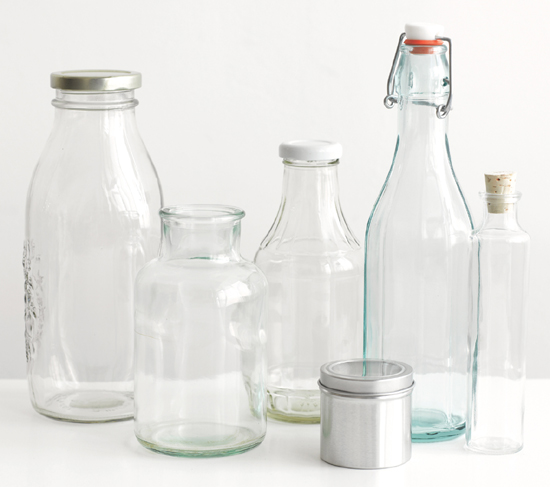 A row of different-sized, empty, clean, glass jars and bottles