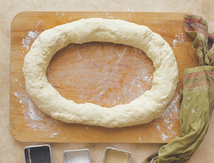 A large ring of dough on a wooden cutting board