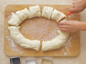 Cutting a large ring of dough into evenly sized pieces