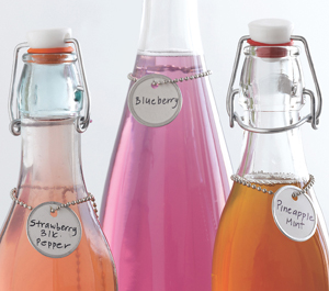 Glass bottles full of colorful syrup and labels with round tags