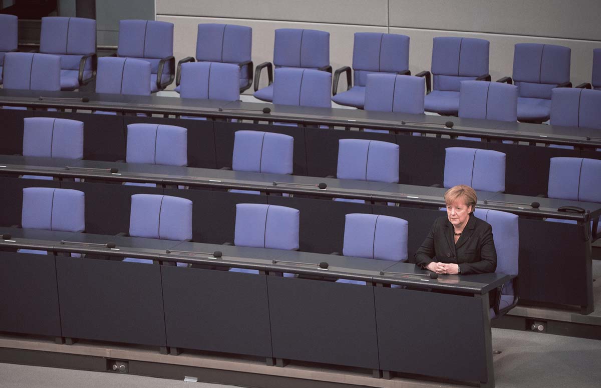 Angela Merkel sitzt ganz rechts in der erste Reihe, die anderen Plätze neben und hinter ihr sind leer.