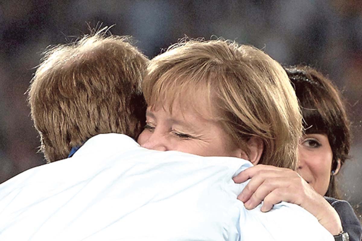 Angela Merkel umarmt Jürgen Klinsmann, die Augen geschlossen.