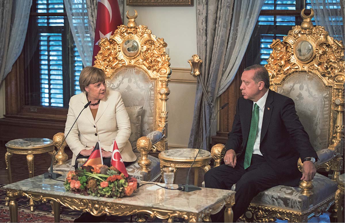 Recep Tayyip Erdoğan und Angela Merkel sitzen nebeneinander auf zwei riesigen vergoldeten Stühlen, vor sich ein vergoldeter Tisch, jeweils neben ihnen vergoldete Beistelltische