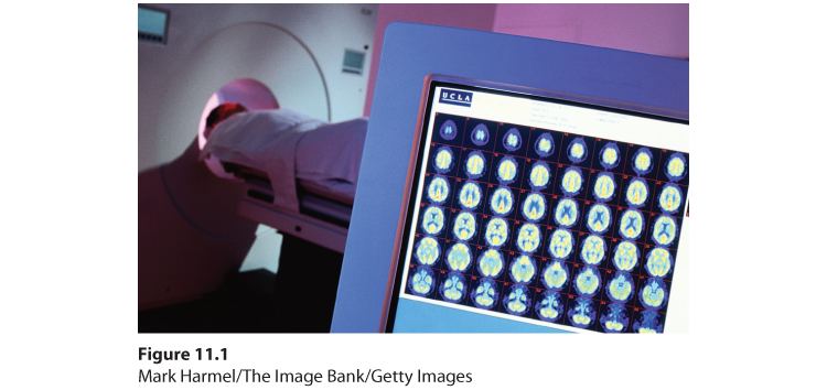 Photograph of a PET machine. It shows a person in the machine and the screen displaying the images of the brain.