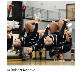 Photograph of high school cheerleaders performing a flip.