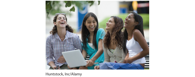 Photograph of four girls sitting together and laughing.