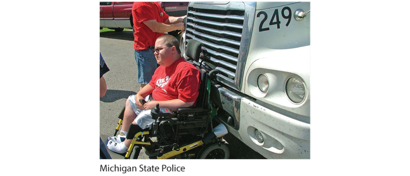 A photo of a man in a wheelchair sitting in front of a truck.