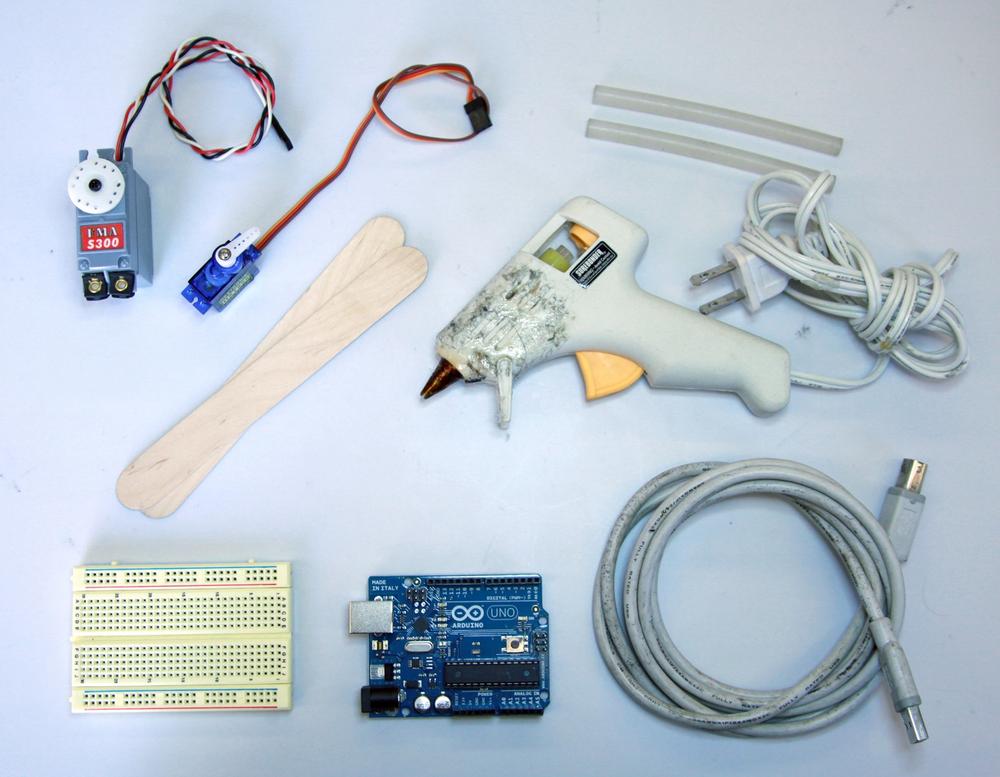 All the supplies you’ll need to build the robot arm: an Arduino, a breadboard, two servos, two popsicle sticks, a USB A/B cable, a hot glue gun, and some hot glue.