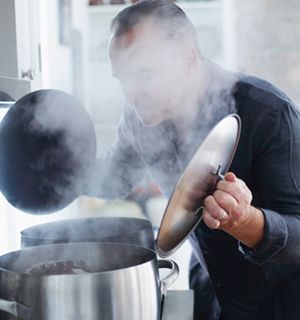 A man looking into two steaming pots