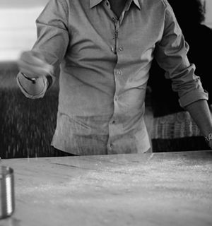 A man sprinkling dough on a large counter