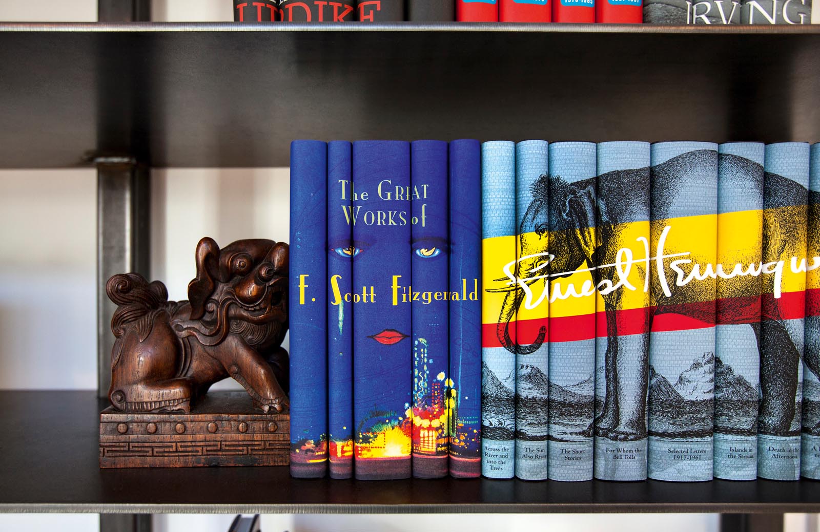 Photo of shelved books with author-related images on groups of the jacket spines.