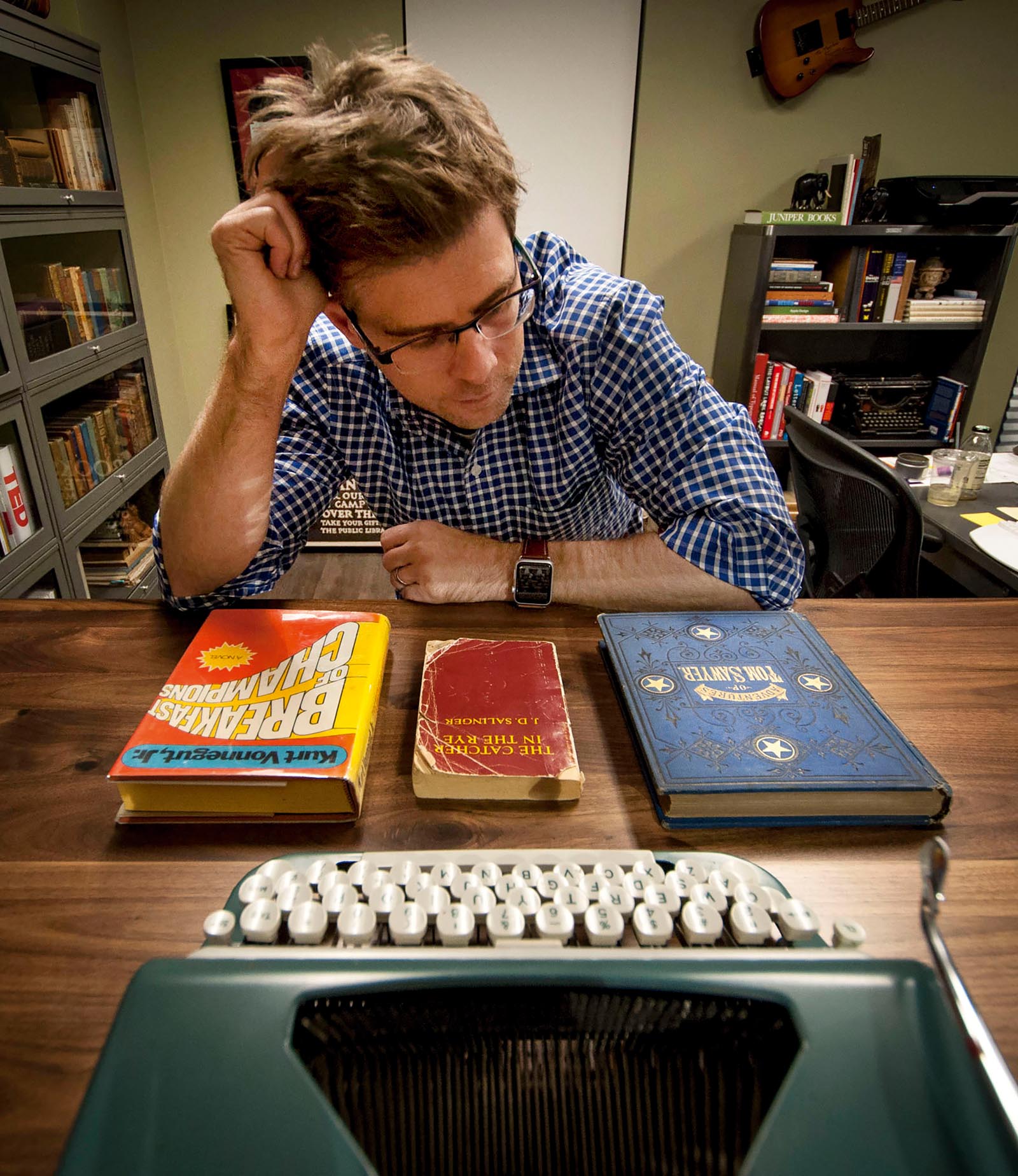 Photo of Thatcher contemplating books with widely varied appearances.